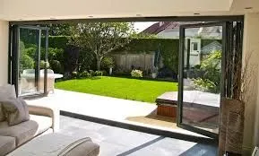 Interior view through open bifold doors to a lawn and garden