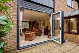 Open bifold door at a brick house, showing the lower threshold and track area